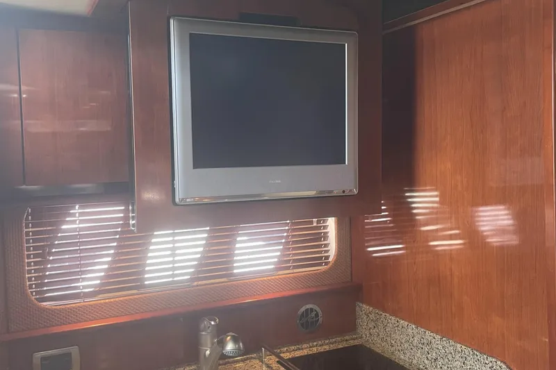 Slide: The Image of Interior of 2006 Sea Ray 380 Sundancer with TV, wooden cabinets, and granite countertop. - 22