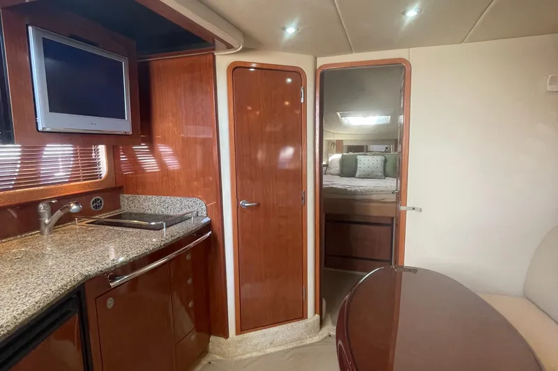 Slide: The Image of 2006 Sea Ray 380 Sundancer interior with kitchenette, wood cabinetry, and cozy bedroom. - 23