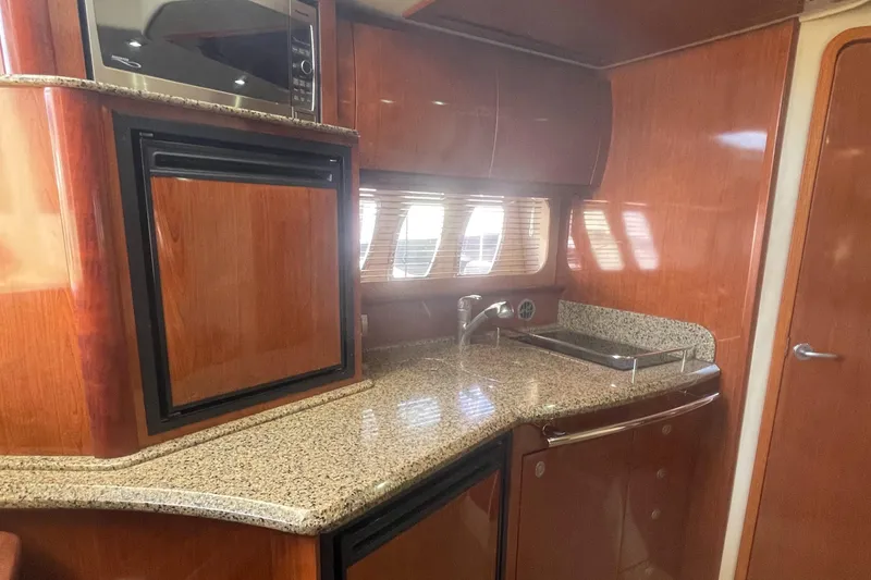 Slide: The Image of 2006 Sea Ray 380 Sundancer yacht interior with kitchenette, featuring wood cabinetry and granite countertops. - 8