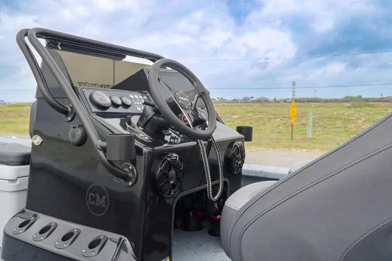 Slide: The Image of 2025 Haynie 24 High Output boat dashboard with steering wheel and controls, set against a scenic backdrop. - 21