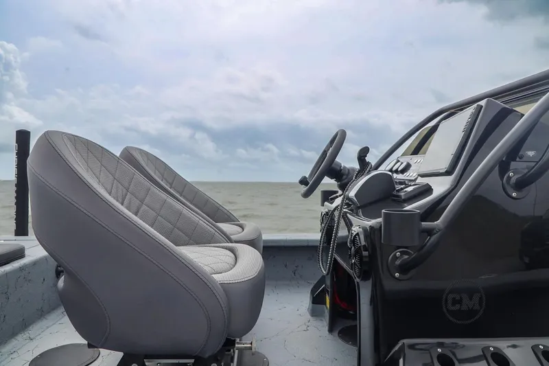 Slide: The Image of 2025 Haynie 24 High Output boat interior with steering wheel and seats, overlooking the ocean. - 30