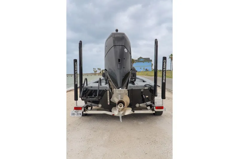 Slide: The Image of Rear view of 2025 Haynie 24 High Output boat on trailer, overcast sky. - 44