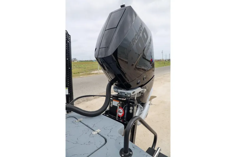 Slide: The Image of 2025 Haynie 24 High Output boat with Mercury outboard motor, parked on a coastal road. - 49