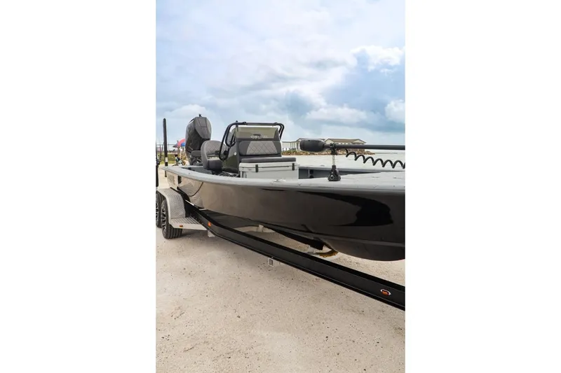 Slide: The Image of 2025 Haynie 24 High Output boat on trailer, sleek black design under cloudy sky. - 5
