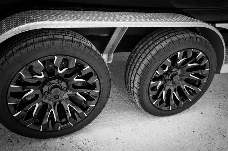 Slide: The Image of 2025 Haynie 24 High Output trailer wheels, black rims, diamond plate fender, close-up view. - 7