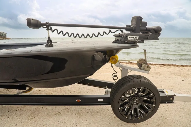 Slide: The Image of 2025 Haynie 24 High Output boat on trailer by the beach, featuring Minn Kota motor. - 9