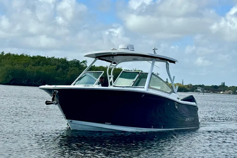 Slide: The Image of 2023 Blackfin 272 DC boat cruising on a calm waterway under a cloudy sky. - 15