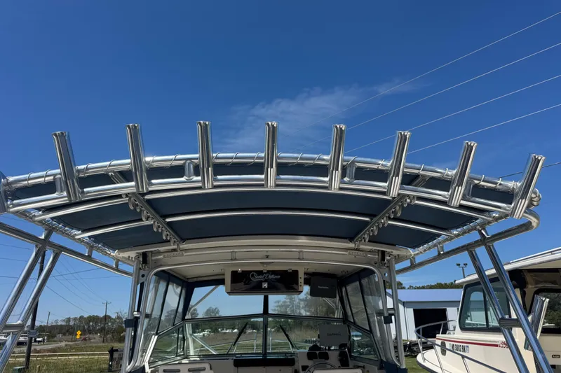 Slide: The Image of 2002 Parker 2510 Walkaround boat with rod holders and canopy under a clear blue sky. - 16