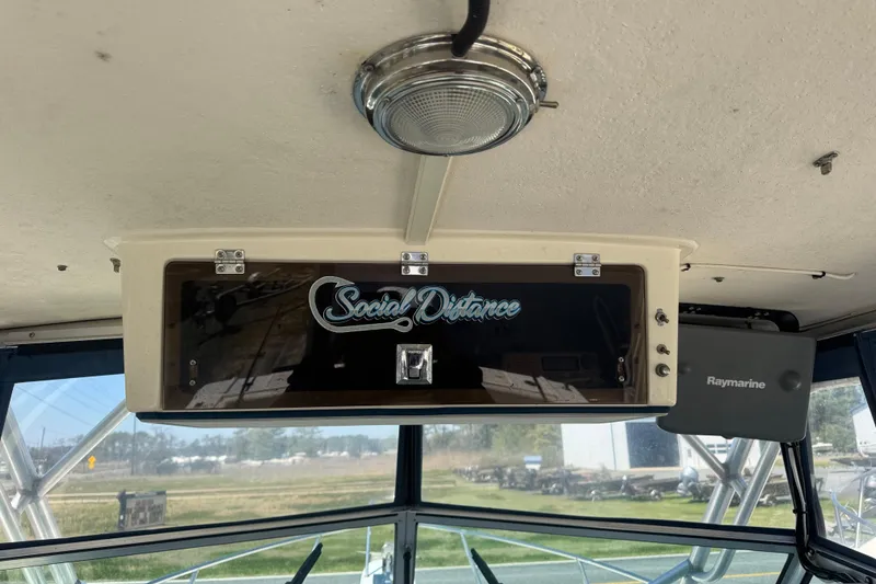 Slide: The Image of Interior of 2002 Parker 2510 Walkaround boat with "Social Distance" sign and Raymarine equipment. - 6