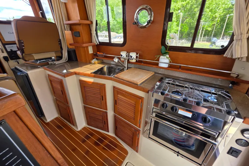 Slide: The Image of Interior of 2020 Ranger Tugs R-31 CB, featuring a compact kitchen with stove and sink. - 19