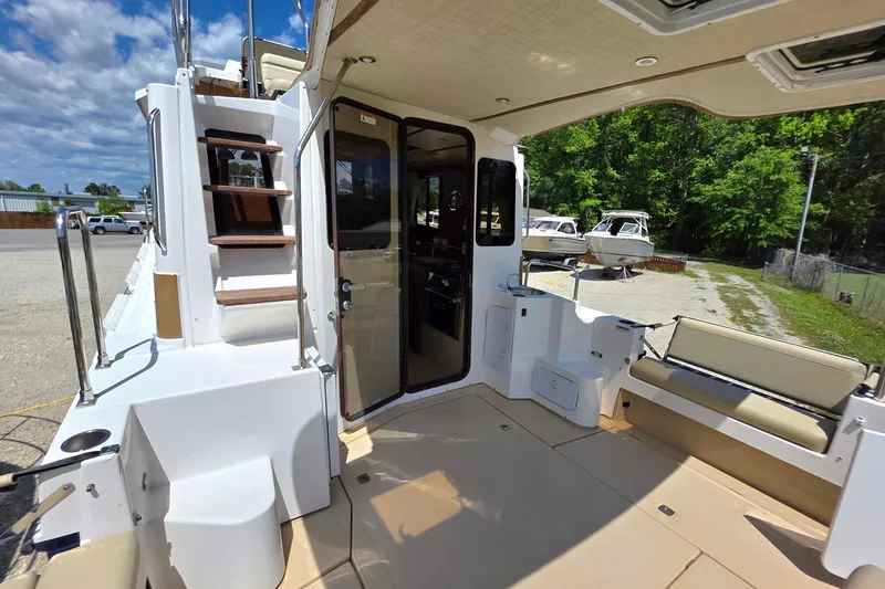Slide: The Image of 2020 Ranger Tugs R-31 CB boat interior with seating and stairs under a blue sky. - 8