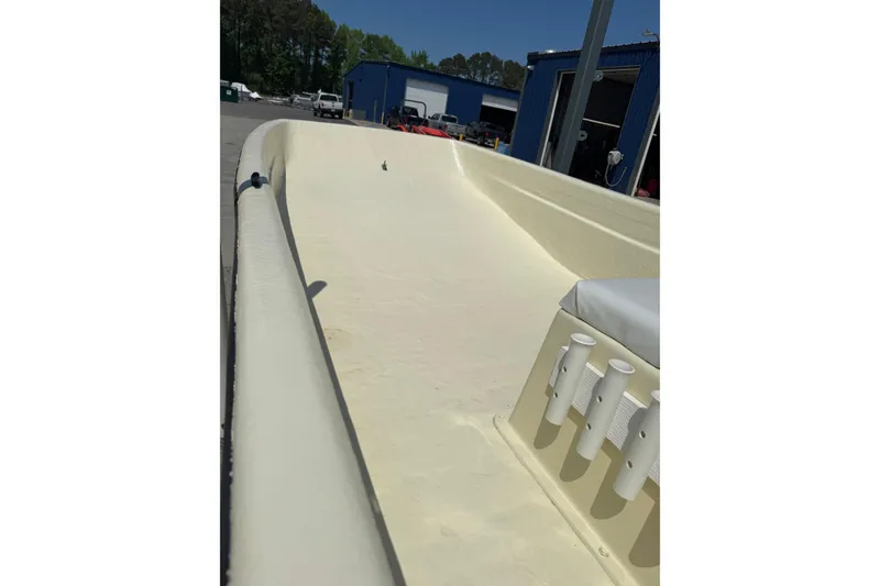 Slide: The Image of 1998 Carolina Skiff Semi-Vee 19 boat interior with rod holders, docked near blue building. - 5