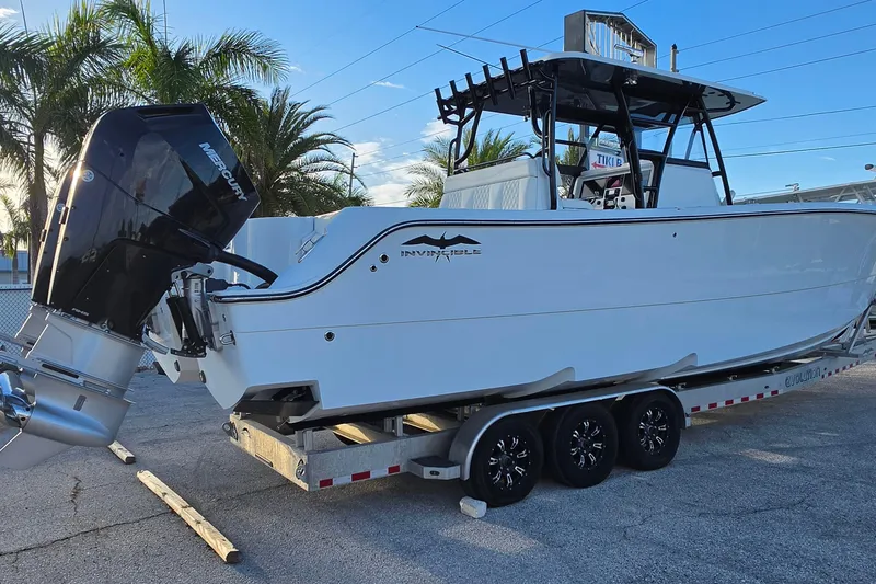 Slide: The Image of 2026 Invincible 33 Catamaran on trailer, featuring Mercury outboard engine, parked near palm trees. - 5
