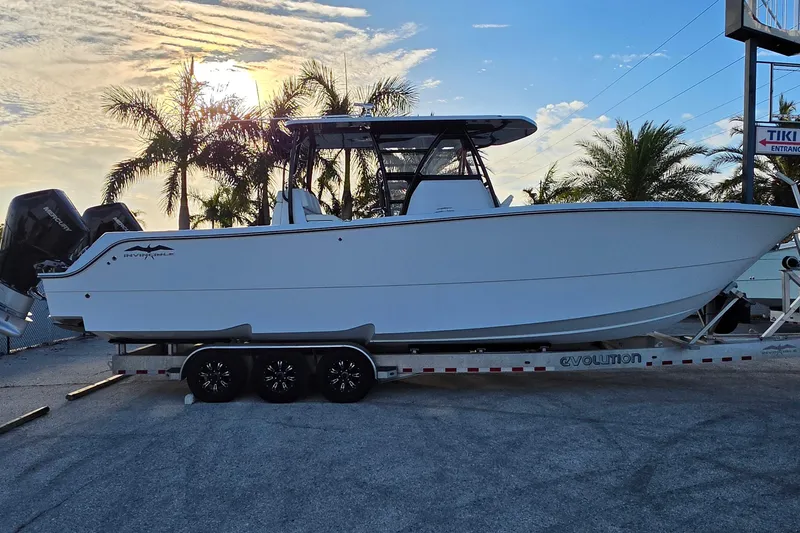 Slide: The Image of 2026 Invincible 33 Catamaran on trailer, parked with palm trees and sunset in background. - 6