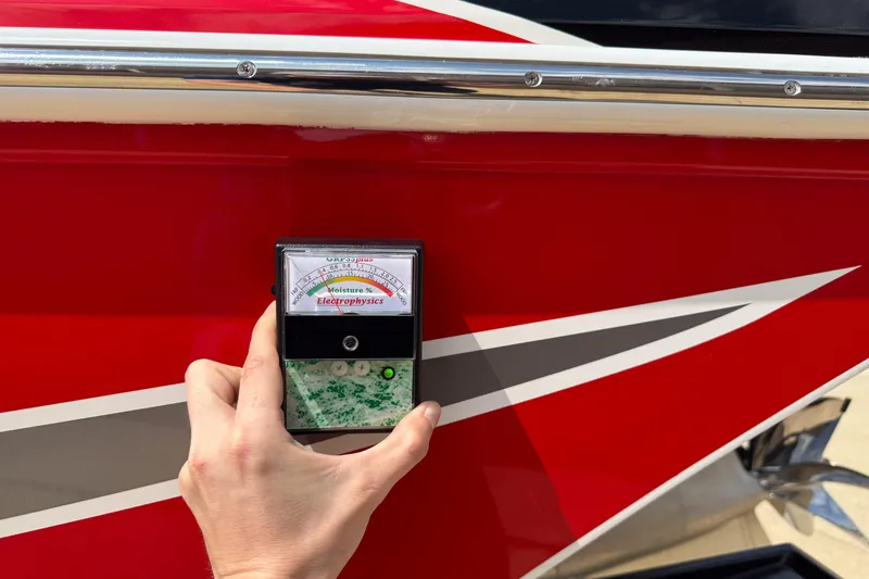 Slide: The Image of Hand holding moisture meter against red 2007 Fountain 42 Lightning boat hull. - 24