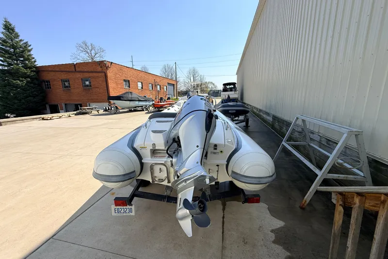 Slide: The Image of 2015 Walker Bay 450 Generation inflatable boat on trailer, parked outdoors near industrial buildings. - 4