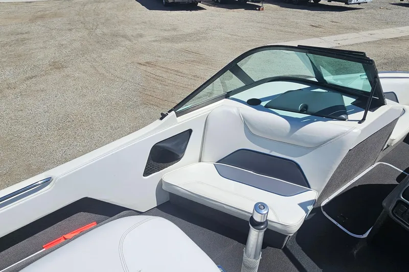 Slide: The Image of 2000 Centurion Sport Bowrider interior with white seating and windshield, parked on gravel. - 8