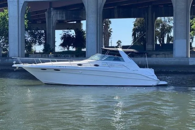 The Image of 1998 Sea Ray Sundancer 330 yacht docked under a bridge on a sunny day. - 0