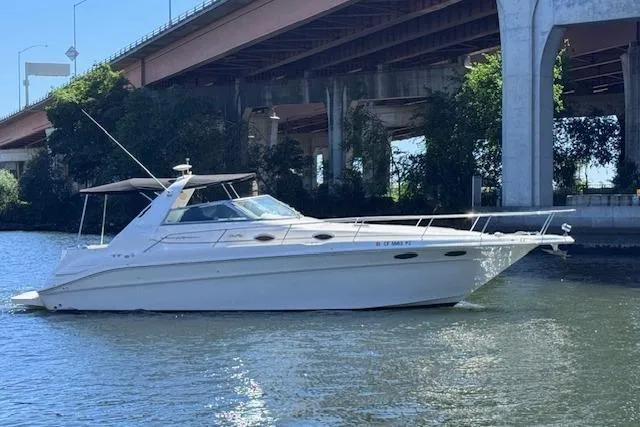 Slide: The Image of 1998 Sea Ray Sundancer 330 yacht cruising under a bridge on a sunny day. - 5