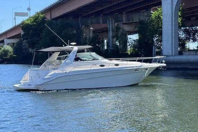 Slide: The Image of 1998 Sea Ray Sundancer 330 yacht cruising under a bridge on a sunny day. - 6