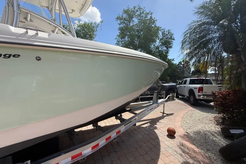 Slide: The Image of 2007 Boston Whaler 270 Outrage boat on trailer, parked near a white truck. - 12