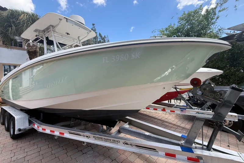 Slide: The Image of 2007 Boston Whaler 270 Outrage boat on trailer, parked outdoors under a clear sky. - 14