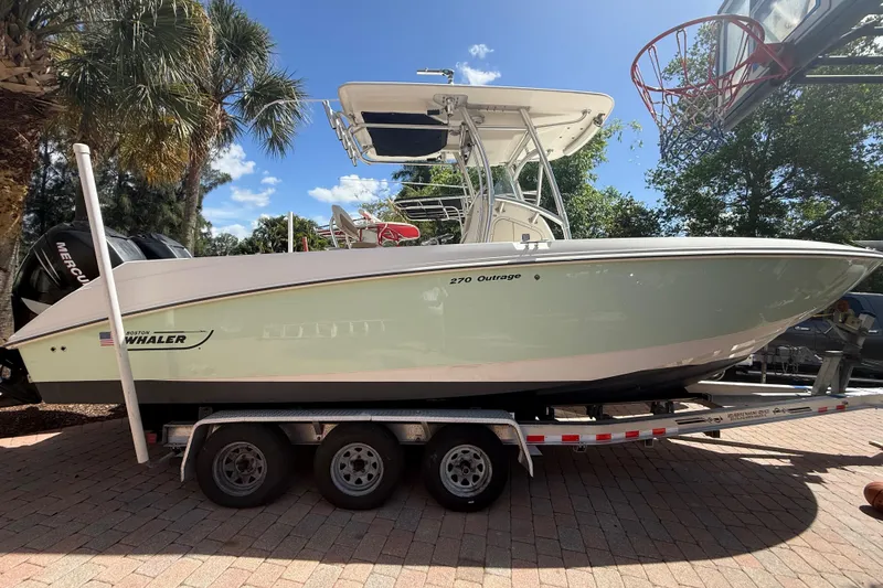 The Image of 2007 Boston Whaler 270 Outrage boat on trailer, parked outdoors under clear sky. - 2
