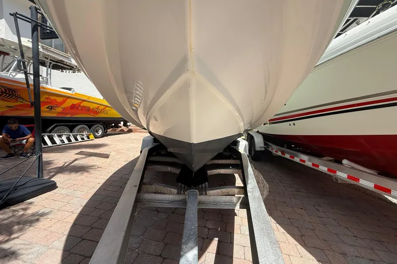 Slide: The Image of 2007 Boston Whaler 270 Outrage boat on trailer, parked between two other boats. - 24