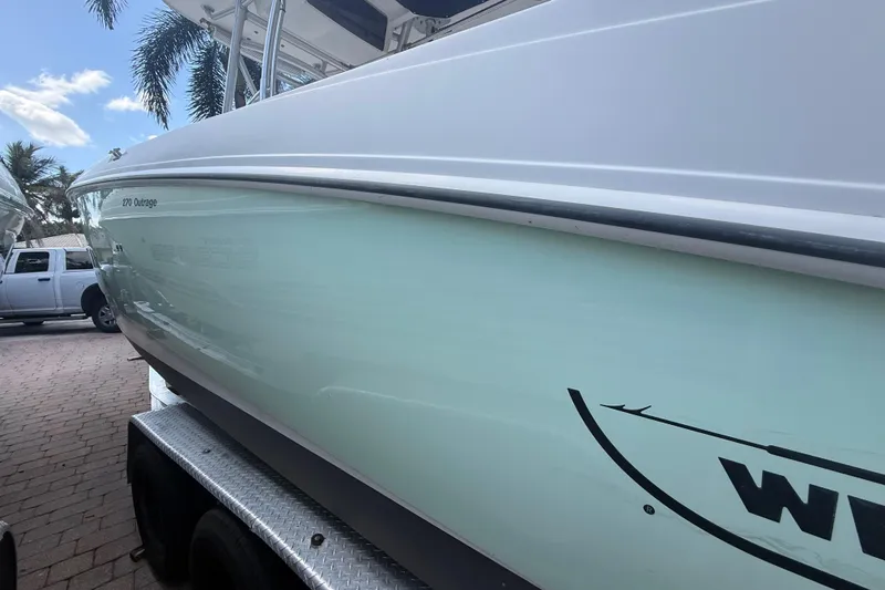 Slide: The Image of 2007 Boston Whaler 270 Outrage boat on trailer, parked outdoors with palm trees. - 5