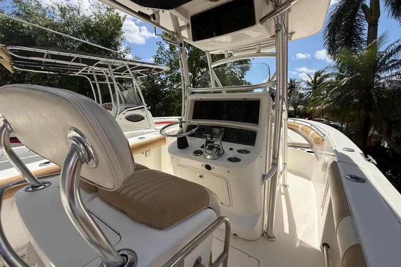 Slide: The Image of 2007 Boston Whaler 270 Outrage boat interior with helm, seating, and palm trees in background. - 59