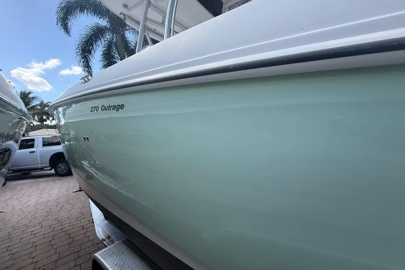 Slide: The Image of 2007 Boston Whaler 270 Outrage boat parked near palm trees and a truck. - 6