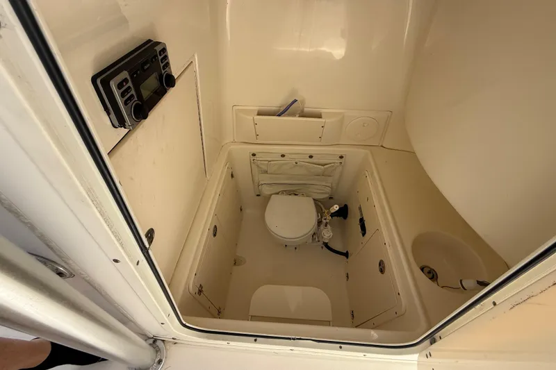 Slide: The Image of Interior of 2007 Boston Whaler 270 Outrage boat, featuring a compact marine toilet. - 69