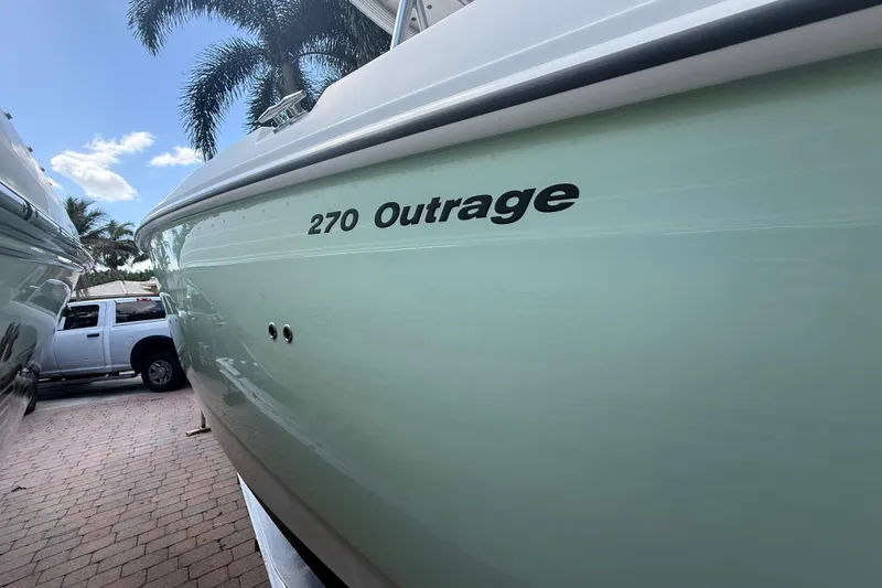 Slide: The Image of 2007 Boston Whaler 270 Outrage boat side view with palm trees and truck. - 7