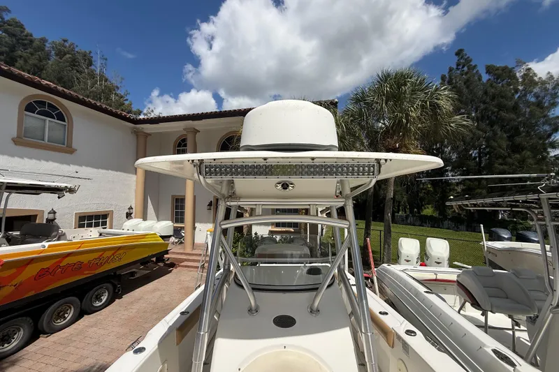 Slide: The Image of 2007 Boston Whaler 270 Outrage boat parked in a driveway with palm trees and blue sky. - 85
