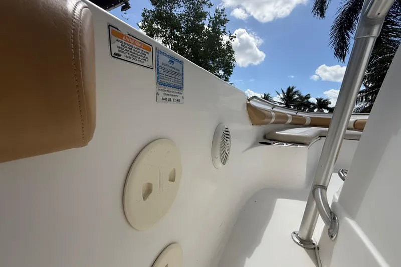 Slide: The Image of 2007 Boston Whaler 270 Outrage interior with seating, safety labels, and railing under a blue sky. - 89
