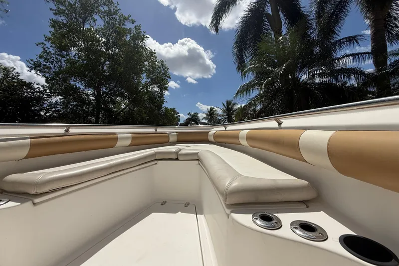Slide: The Image of 2007 Boston Whaler 270 Outrage interior with cushioned seating, surrounded by palm trees and blue sky. - 99