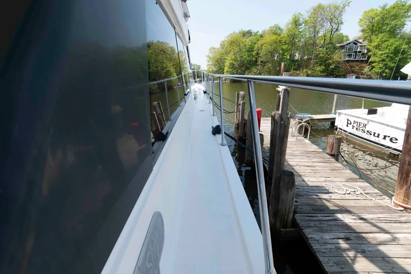 Slide: The Image of 1999 West Bay 58 Sonship Pilothouse MY with striped deck cushions at marina. - 13