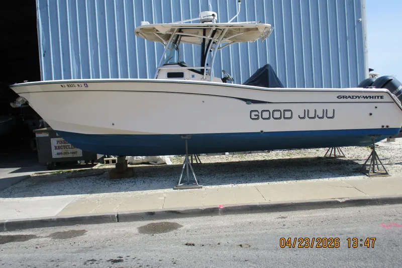 Slide: The Image of 2007 Grady-White Bimini 306 boat named "Good Juju" on stands near a blue building. - 19