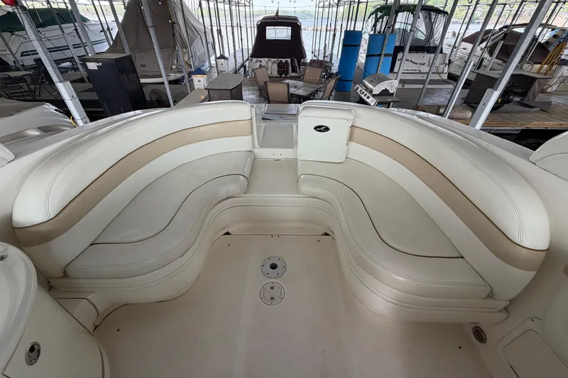 Slide: The Image of 2003 Sea Ray 290 Bow Rider interior with beige seating in a marina setting. - 10