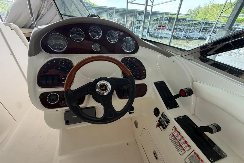 Slide: The Image of 2003 Sea Ray 290 Bow Rider helm with gauges and controls in marina setting. - 20