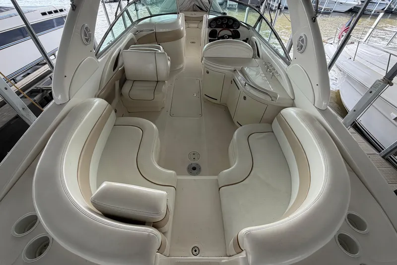 Slide: The Image of 2003 Sea Ray 290 Bow Rider interior with spacious seating and helm, docked at marina. - 9