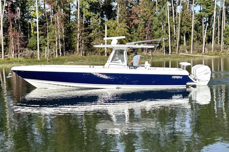 The Image of 2005 Intrepid 370 Center Console boat on calm water, surrounded by trees. - 0