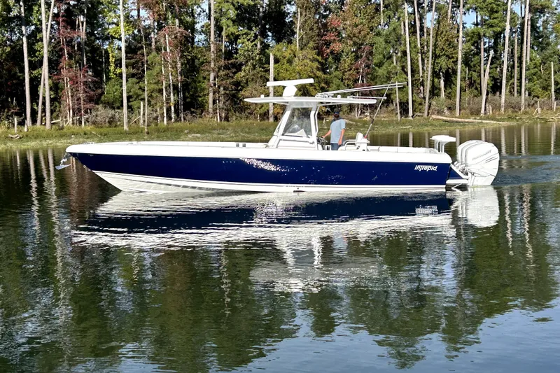 The Image of 2005 Intrepid 370 Center Console boat on calm water, surrounded by trees. - 1