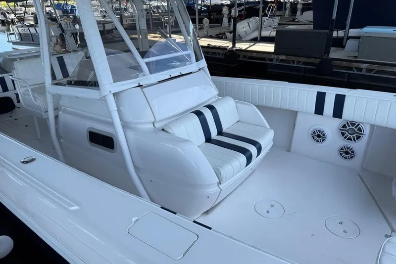 Slide: The Image of 2005 Intrepid 370 Center Console boat with white seating and striped cushions at a marina. - 13