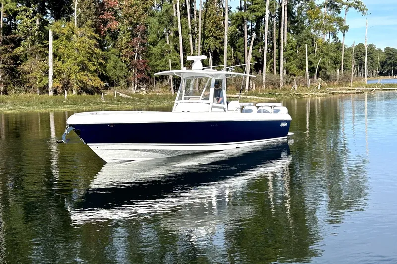Slide: The Image of 2005 Intrepid 370 Center Console boat on calm water, surrounded by trees. - 3