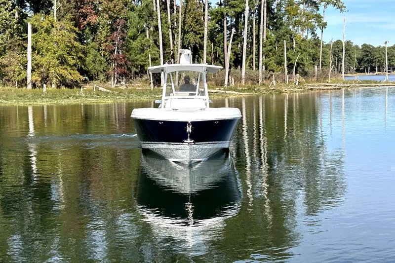 Slide: The Image of 2005 Intrepid 370 Center Console boat cruising on a serene lake with forest backdrop. - 5