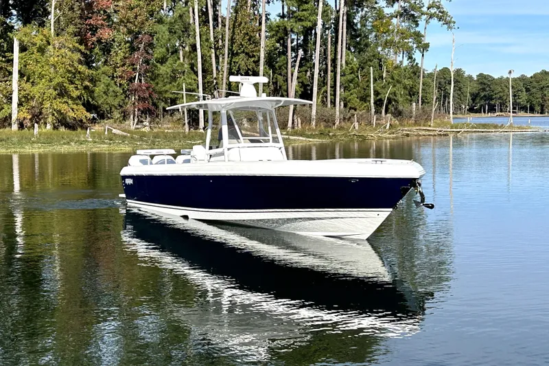 Slide: The Image of 2005 Intrepid 370 Center Console boat on a serene lake with forest backdrop. - 6