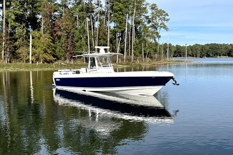 Slide: The Image of 2005 Intrepid 370 Center Console boat on a serene lake with forest backdrop. - 7