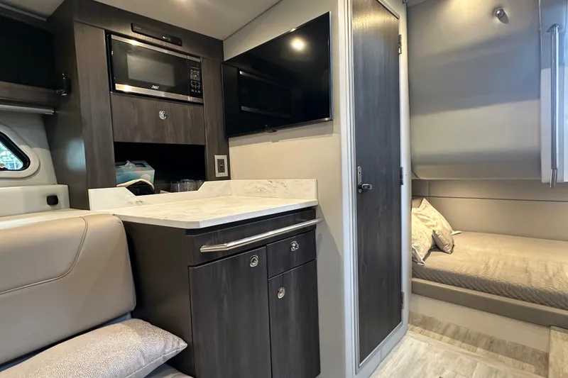 Slide: The Image of 2024 Formula 400 Super Sport Crossover interior with kitchenette, TV, and cozy sleeping area. - 34
