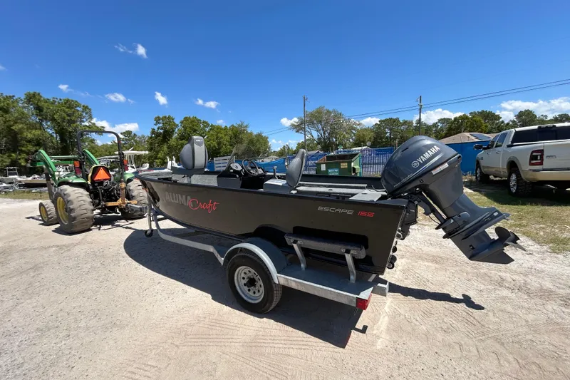 Slide: The Image of 2023 Alumacraft Escape 165 SC boat on trailer, parked outdoors under clear blue sky. - 9